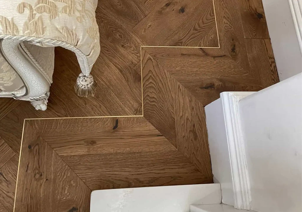 Herringbone parquet wooden floor with white baseboards and cushion
