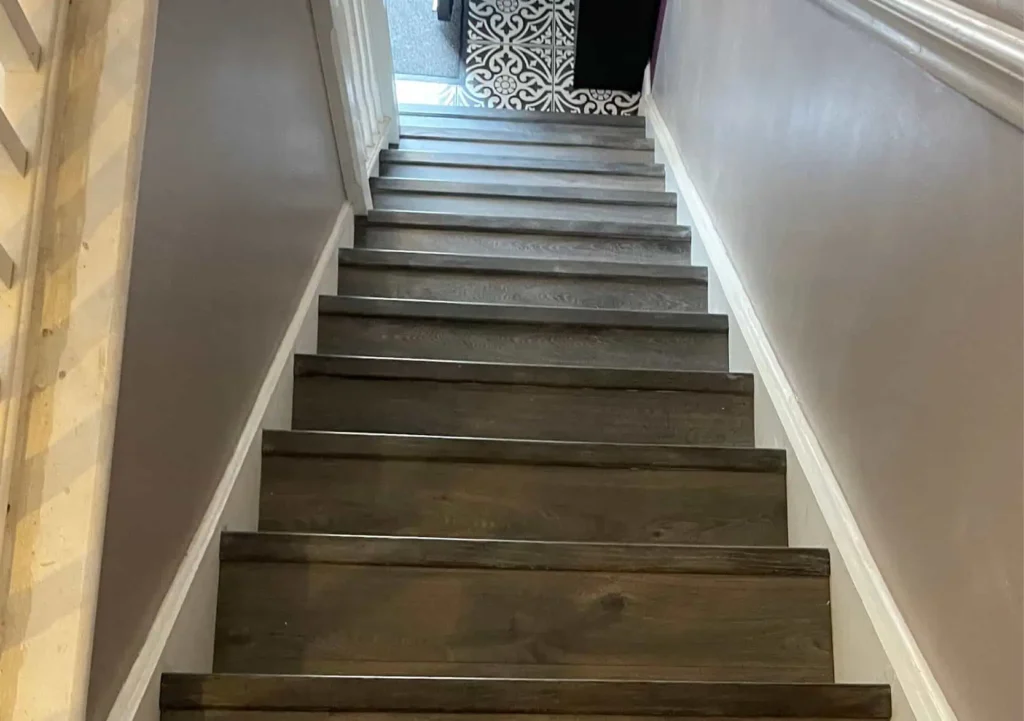 Dark wood staircase with white walls leading upward