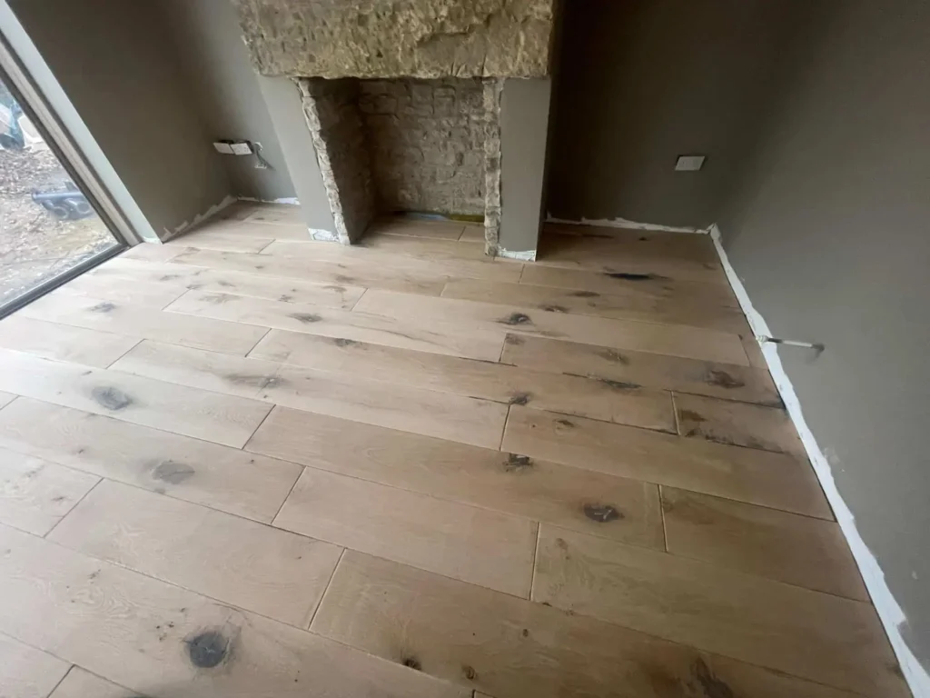 Unfinished room with wooden flooring and concrete pillars