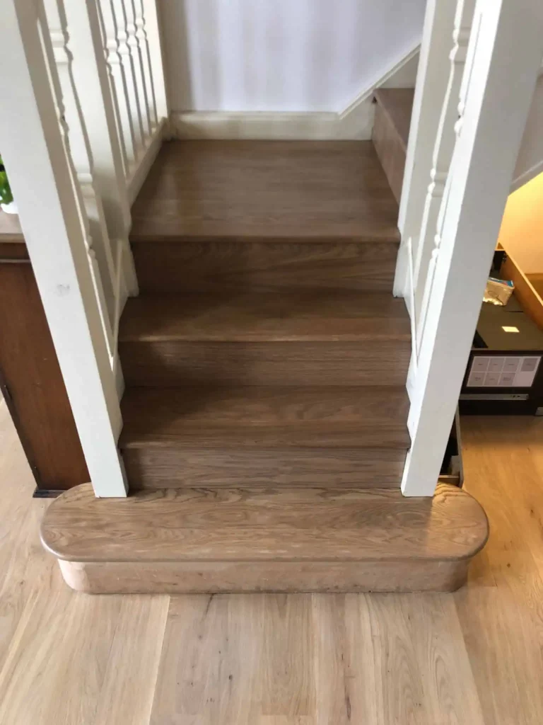 Dark wooden staircase with white railings and trim