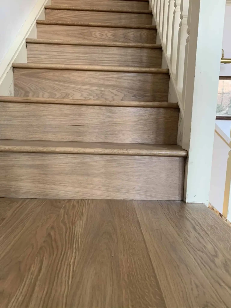 Wooden staircase with white walls and brass handrail
