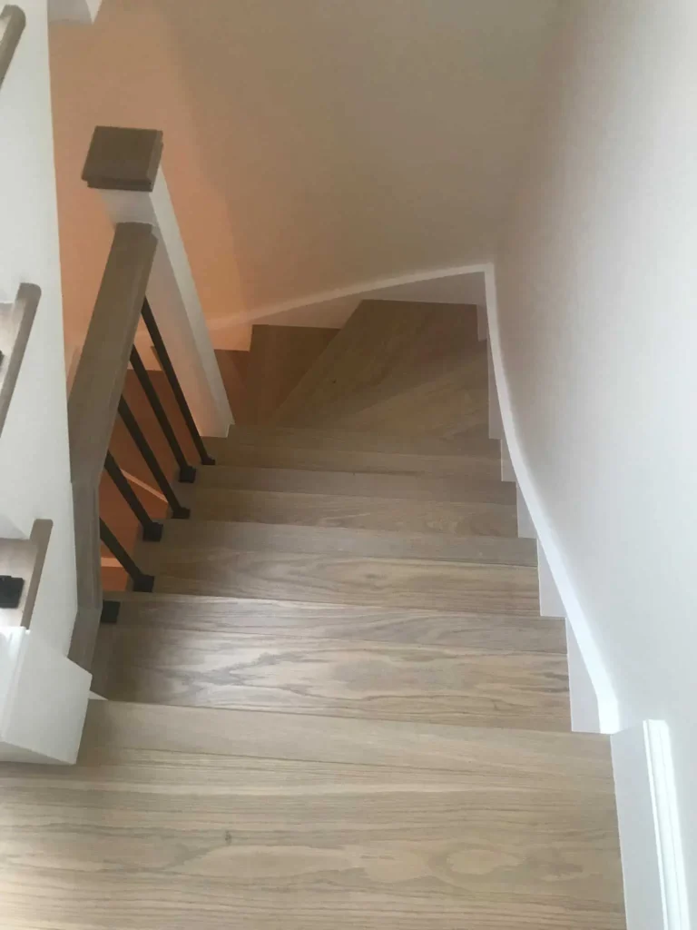 Modern wooden staircase with metal railings and white walls