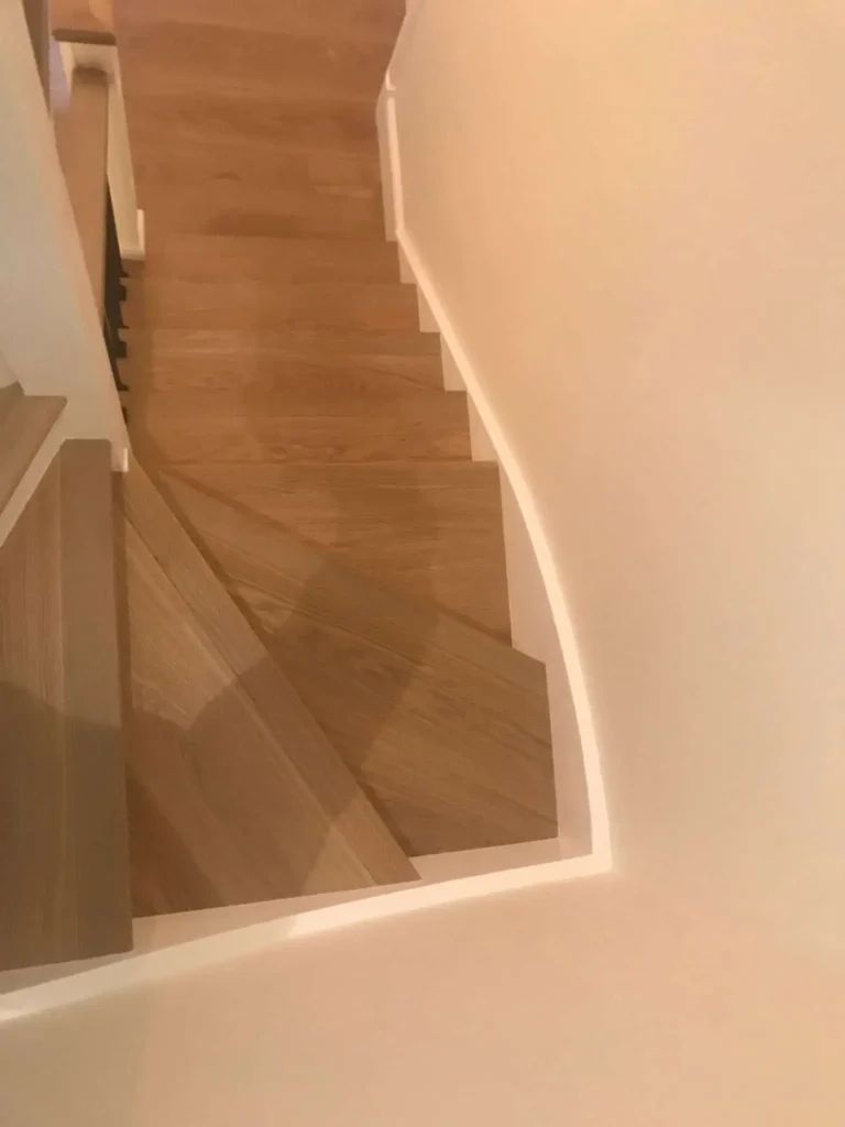 Wooden staircase descending with white walls and handrail