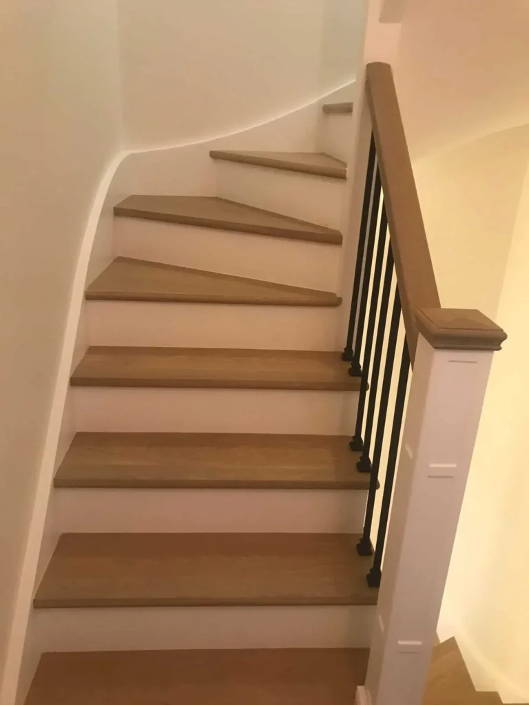 Modern wooden staircase with metal railing and curved walls