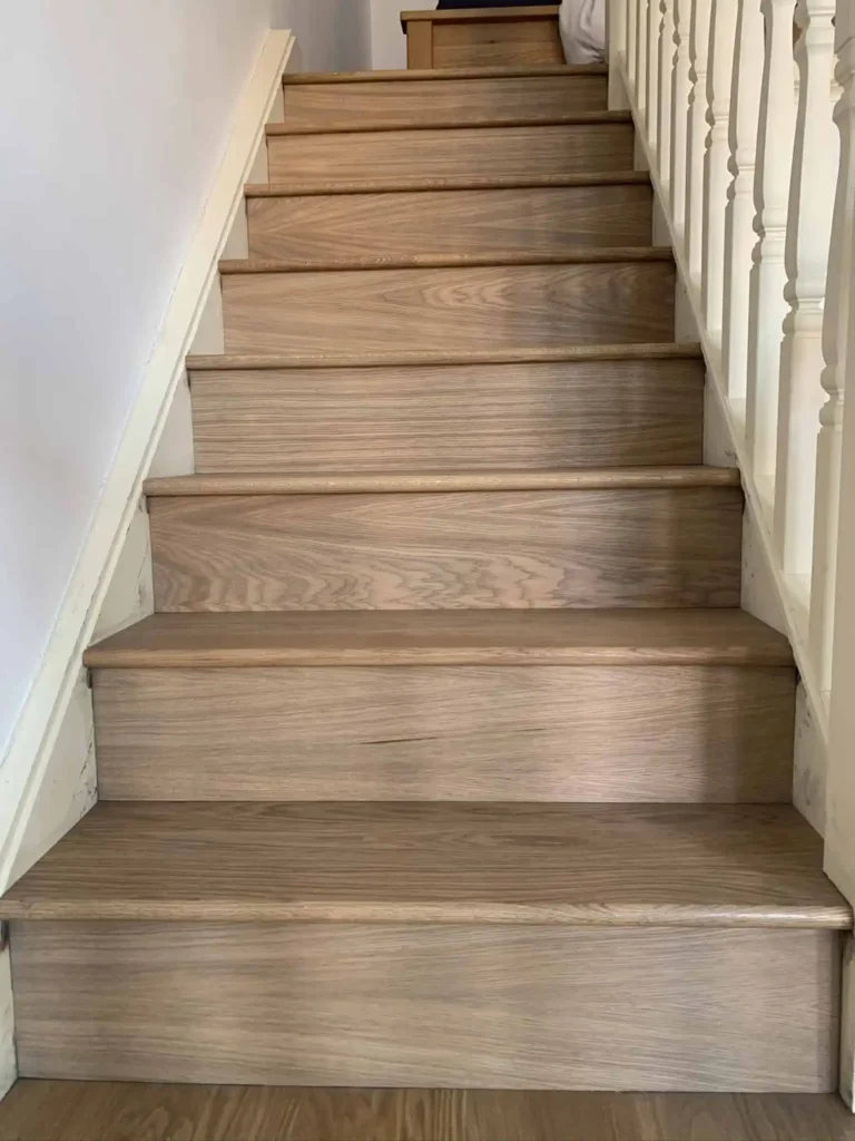 Wooden staircase with white balustrade and cream walls
