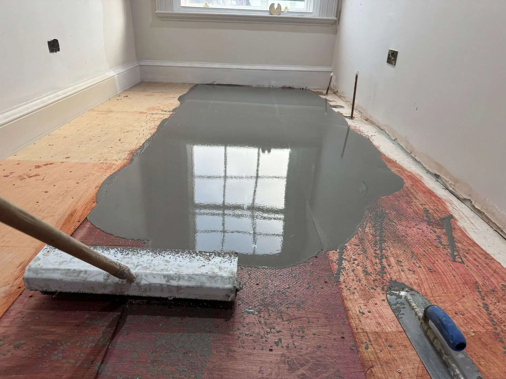 Room undergoing renovation with wet concrete floor levelling