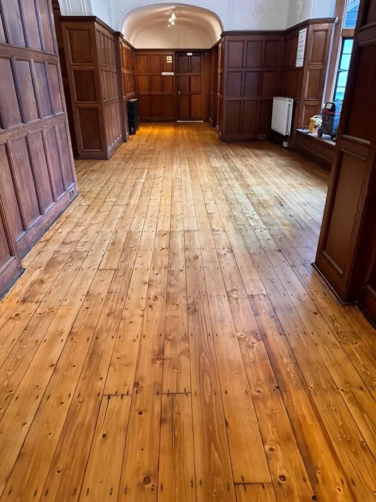 Empty hall with wooden floorboards and dark panelled walls