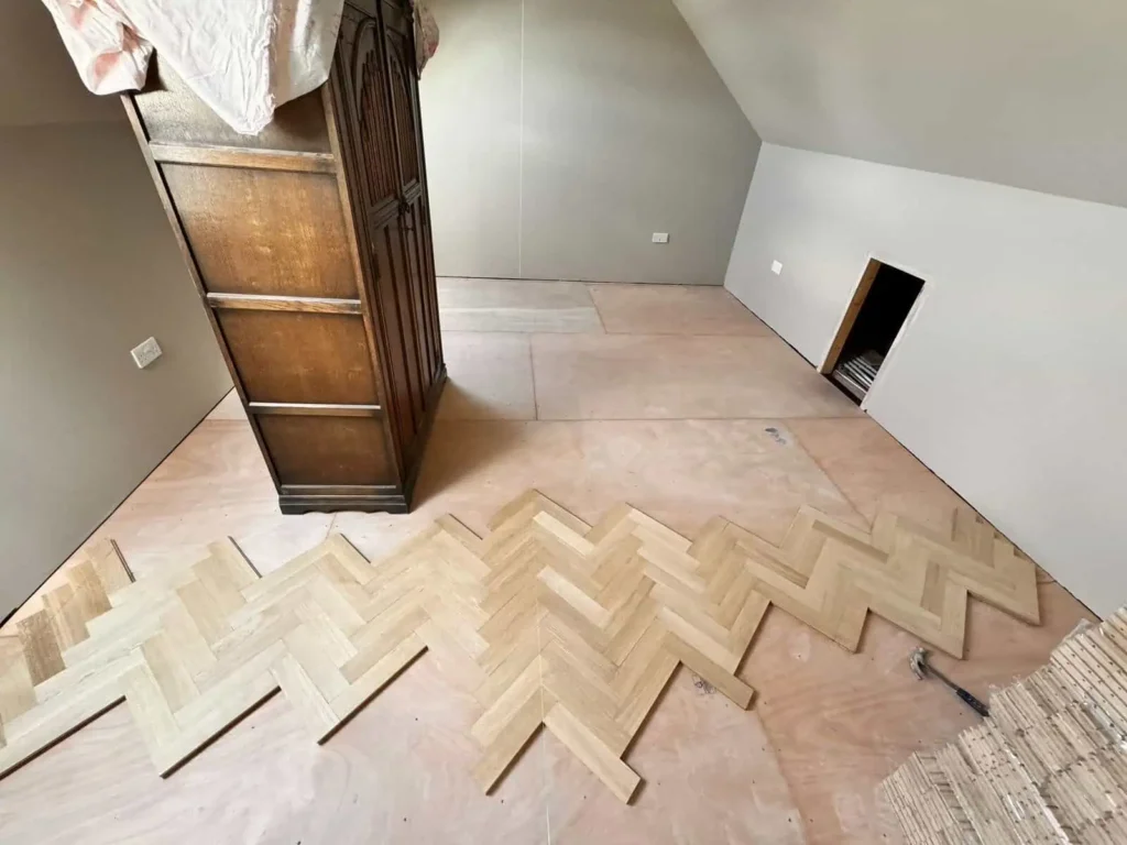 Attic room with herringbone parquet flooring installation in progress
