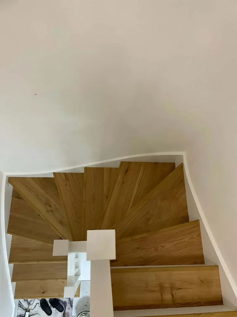 Wooden staircase with white walls and handrail