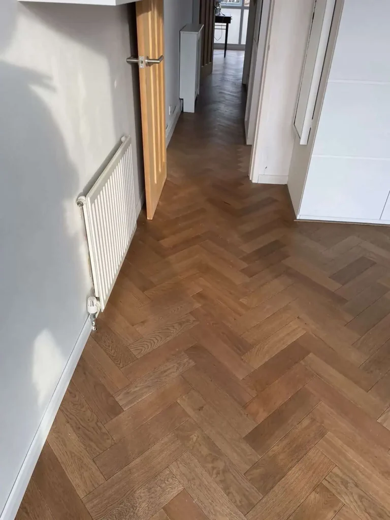 Modern hallway with herringbone wood flooring and white doors