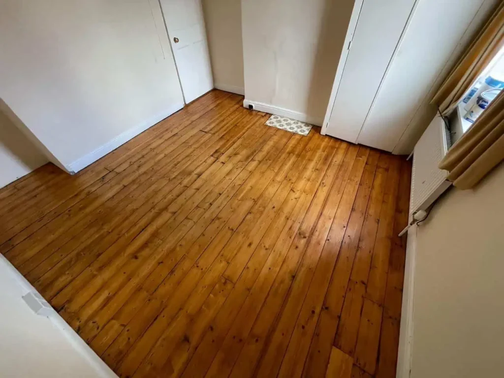 Empty room with wooden floorboards and white built-in wardrobes