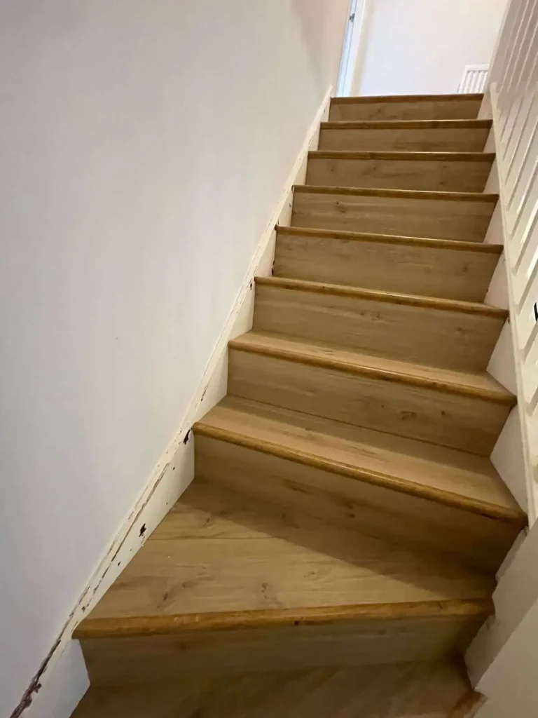 Wooden staircase with white walls leading upstairs