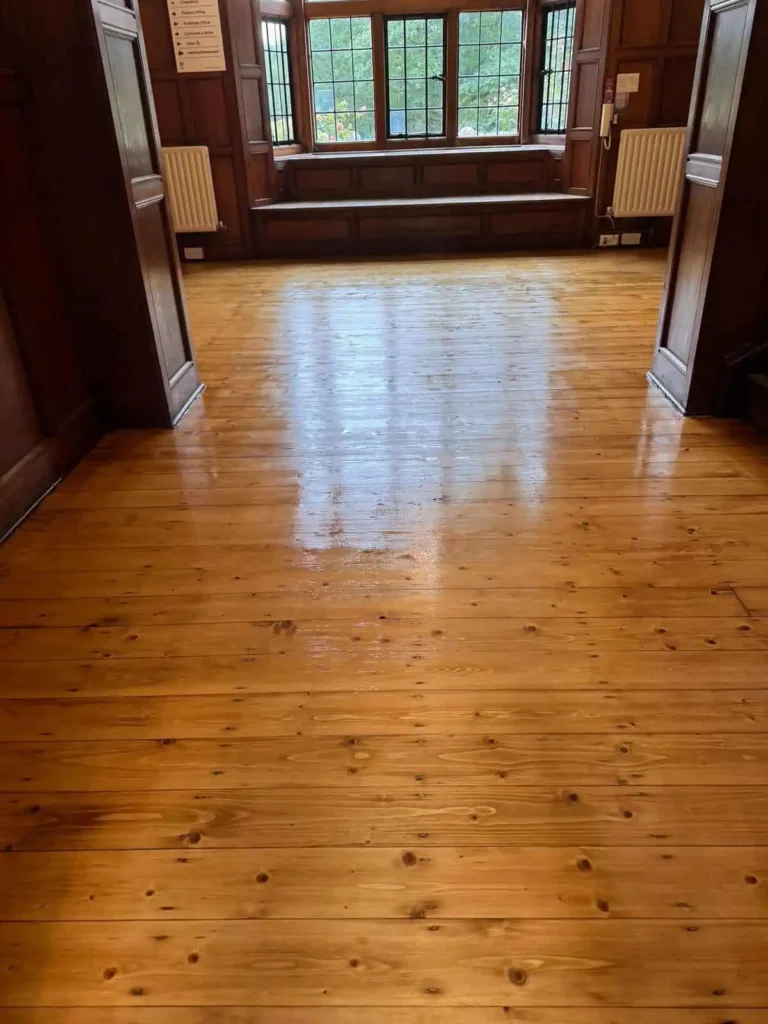 Empty wooden hall with polished floors and large windows