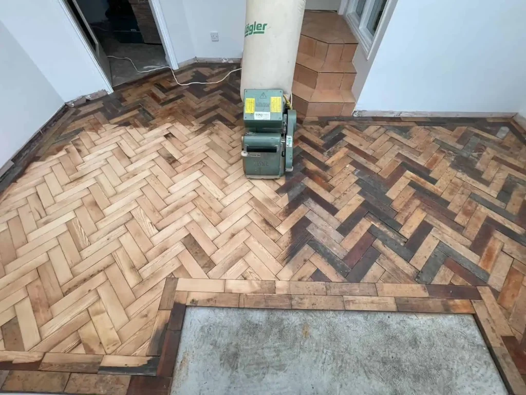 Herringbone parquet floor with floor sanding machine and pillar