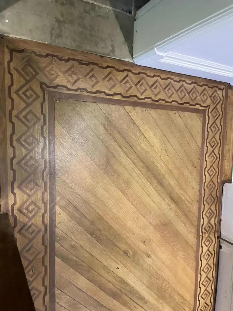Wooden door with decorative inlaid geometric border pattern