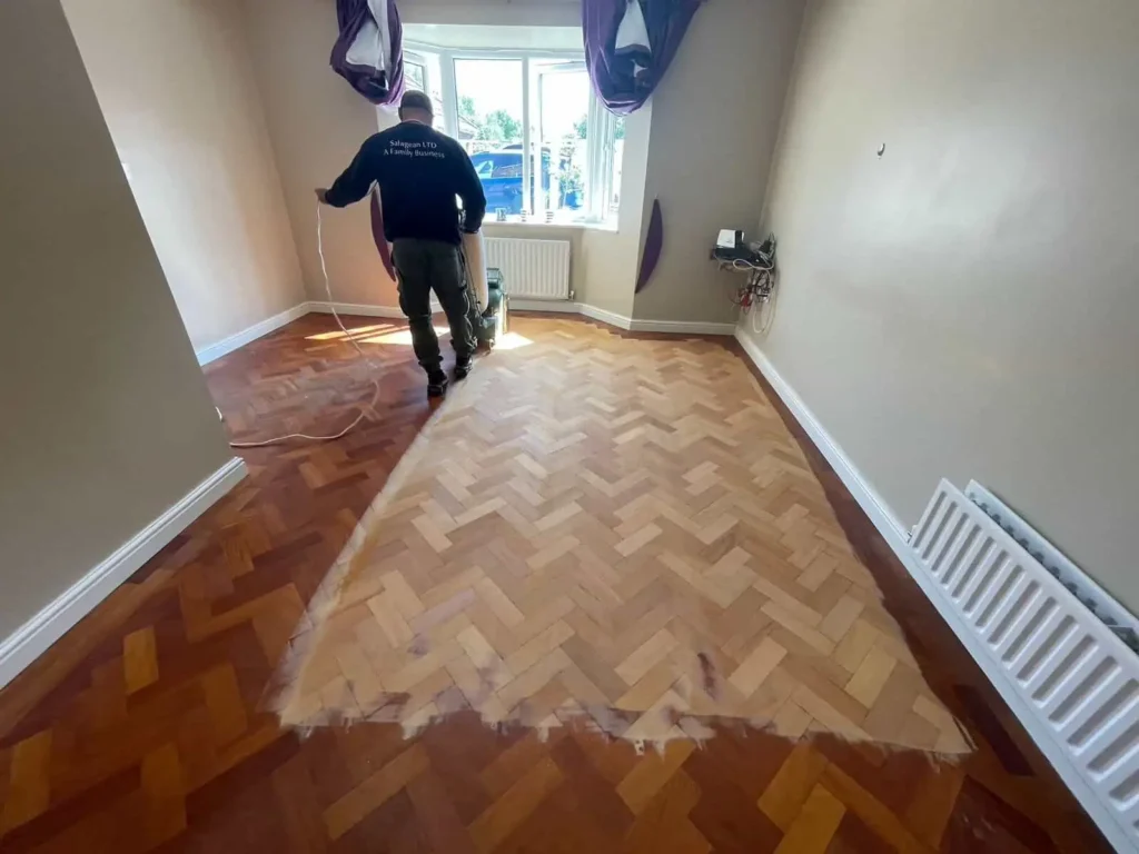 Worker installing herringbone parquet flooring in room