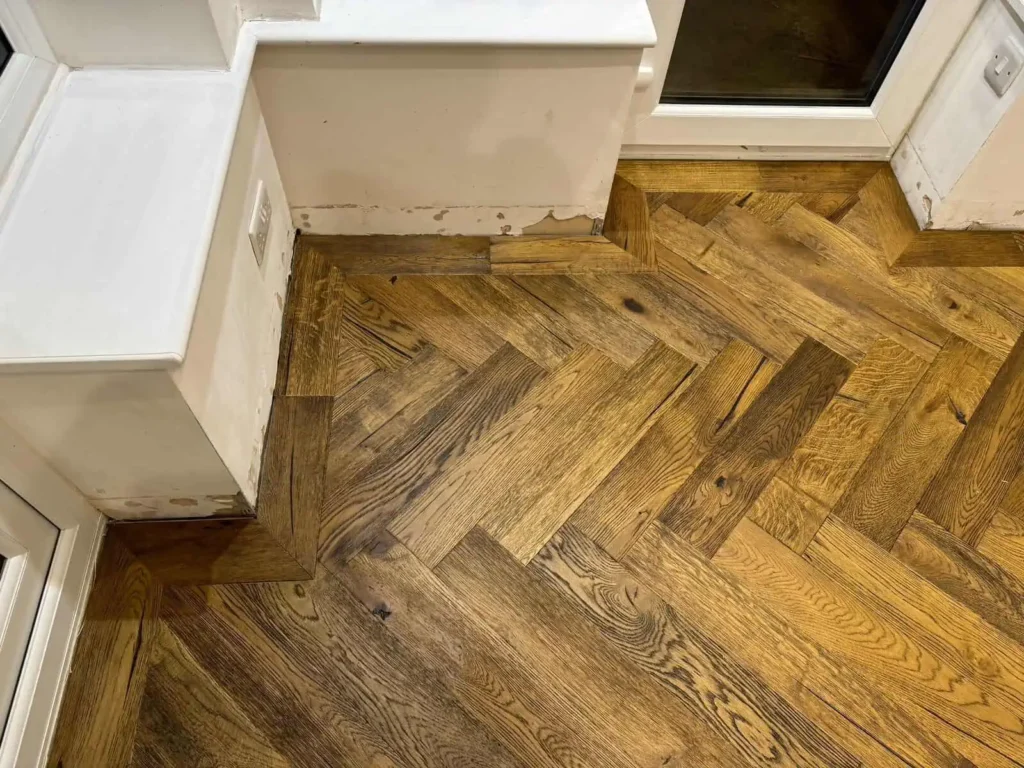 Herringbone parquet wooden floor with white kitchen units