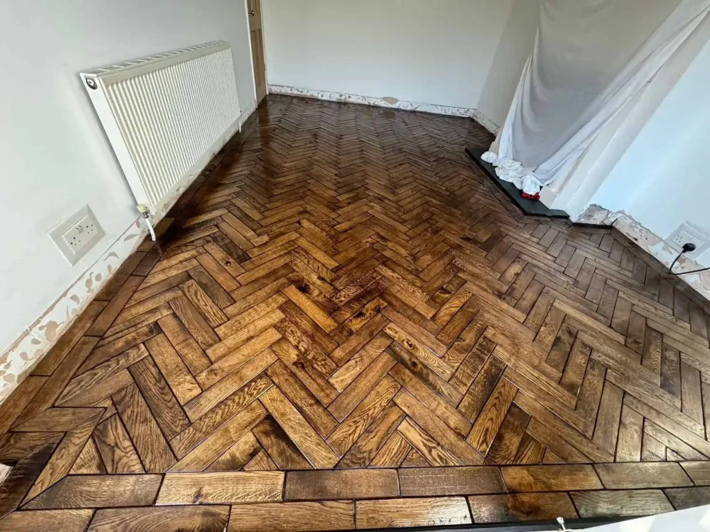 Herringbone parquet wooden floor in empty room with radiator