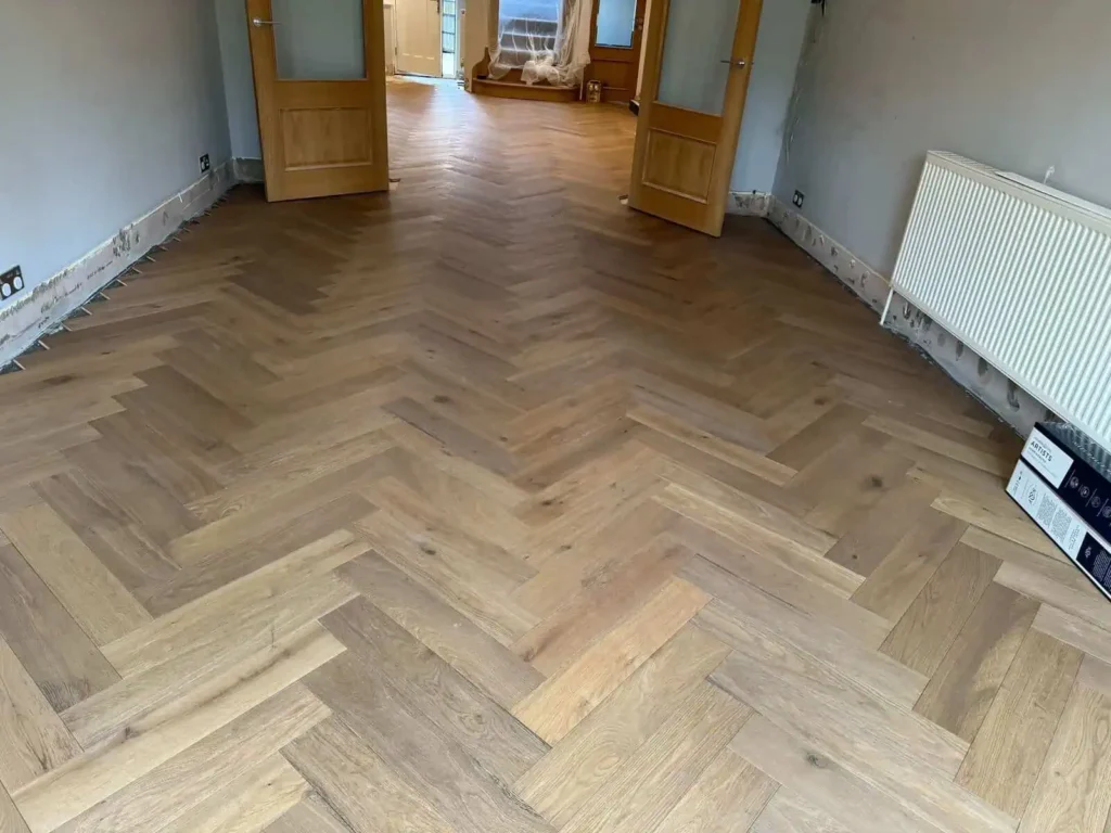 Empty room with herringbone parquet flooring and wooden doors