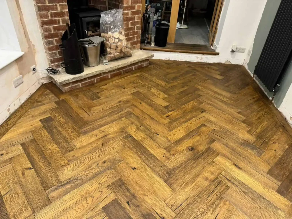 Herringbone wood flooring in living room with fireplace