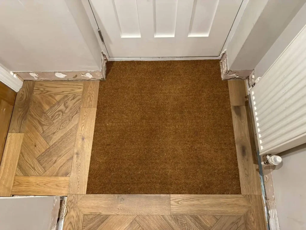 Hallway entrance with brown doormat and wooden flooring