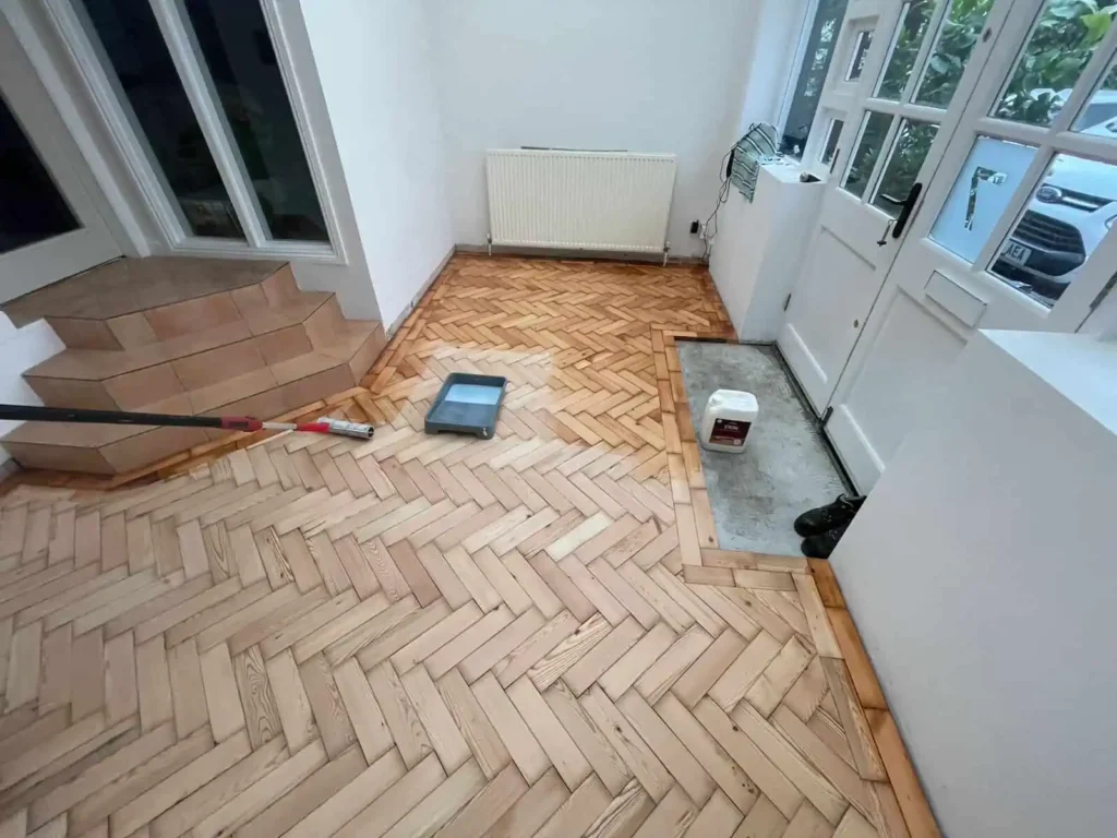 Herringbone wood flooring installation in progress with tools
