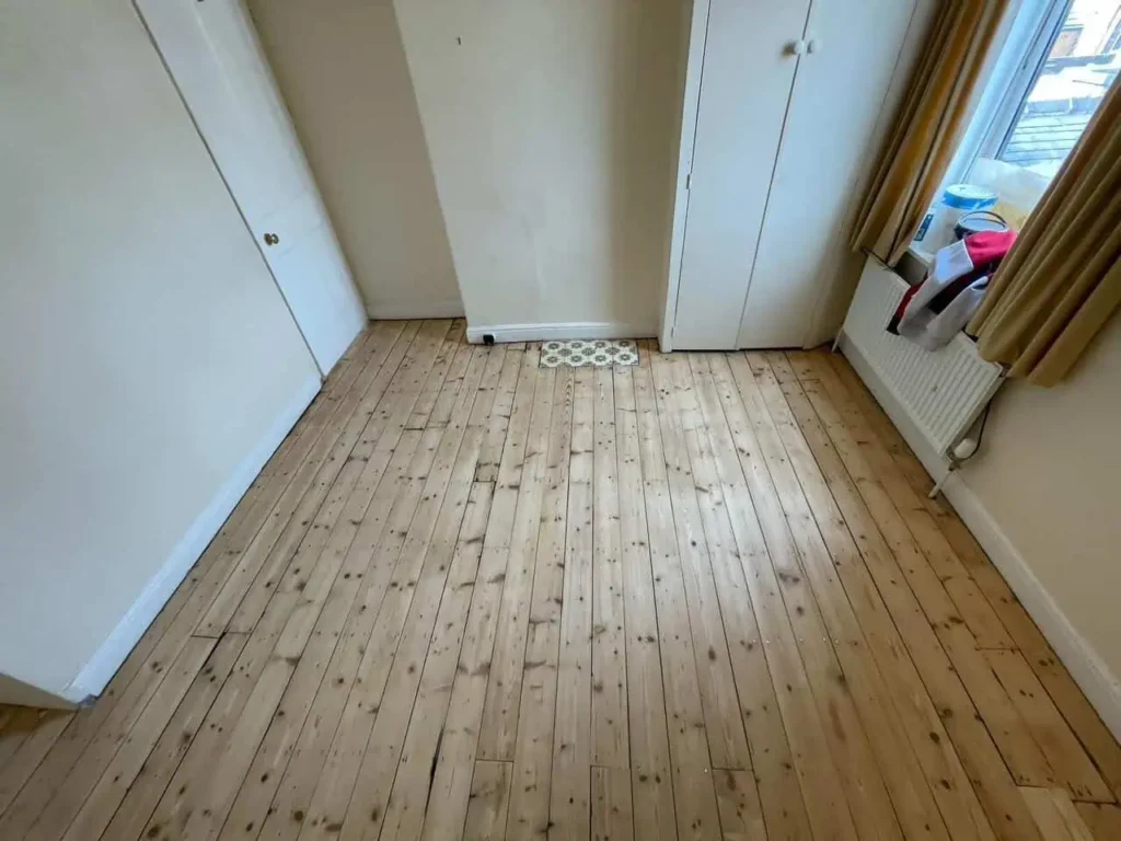 Empty bedroom with wooden floorboards and white doors