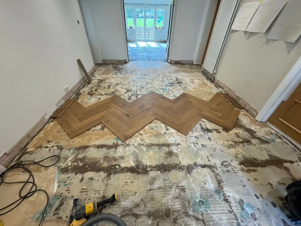 Room undergoing renovation with parquet flooring installation in progress