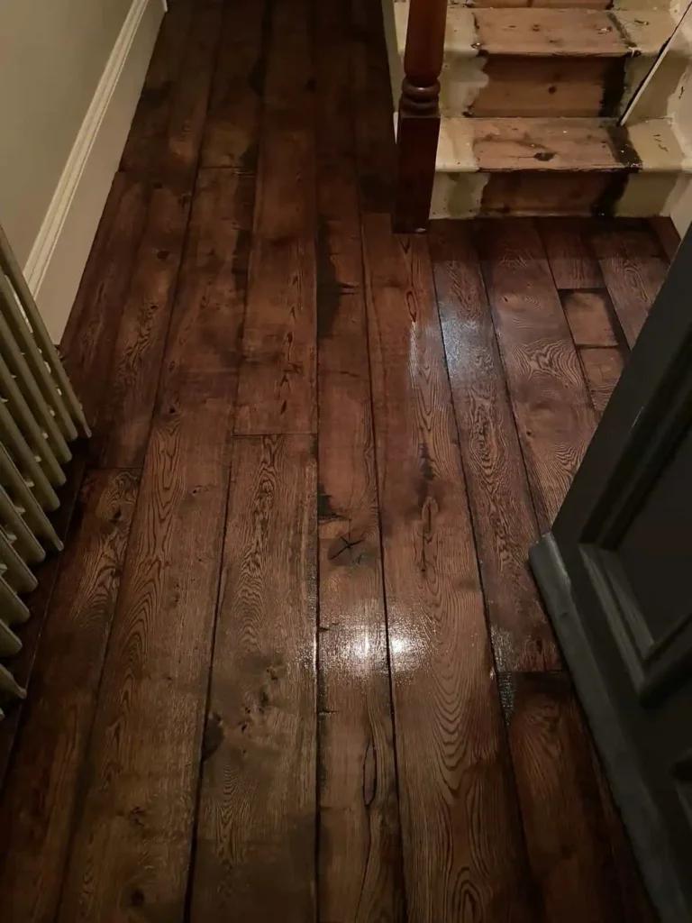 Dark wood flooring with staircase and white skirting board