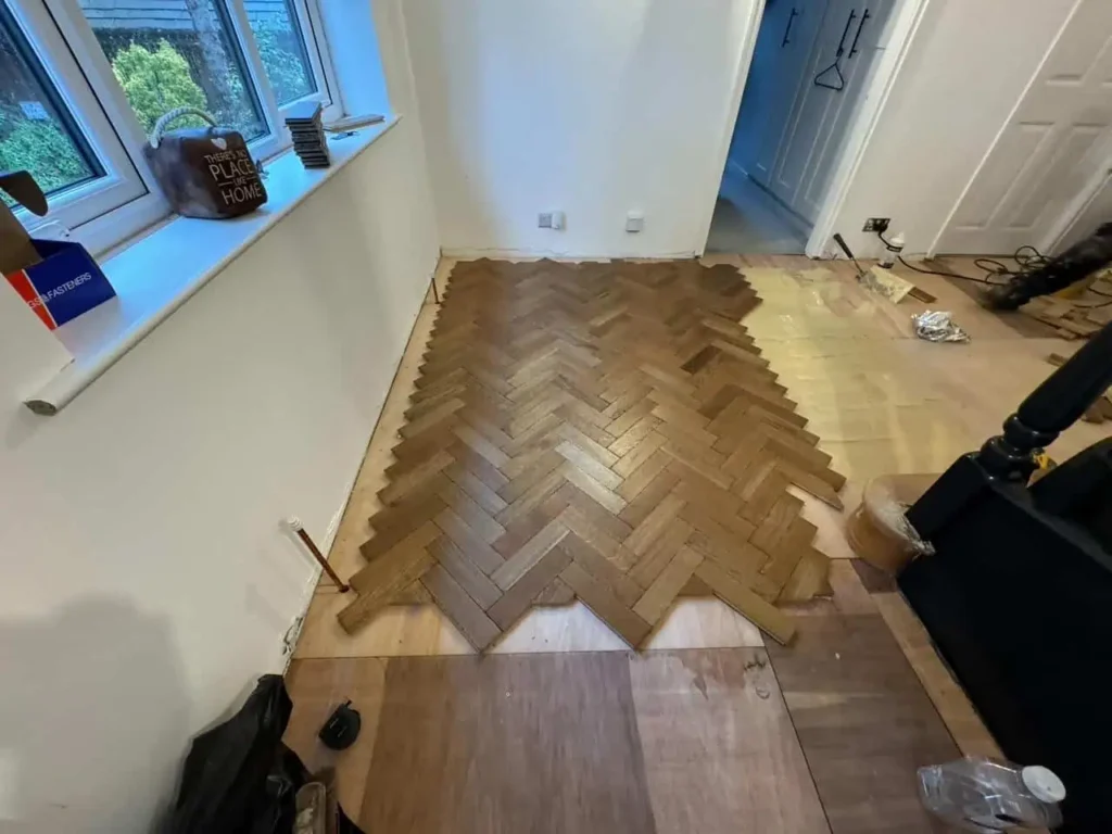 Room interior with herringbone wood flooring installation in progress