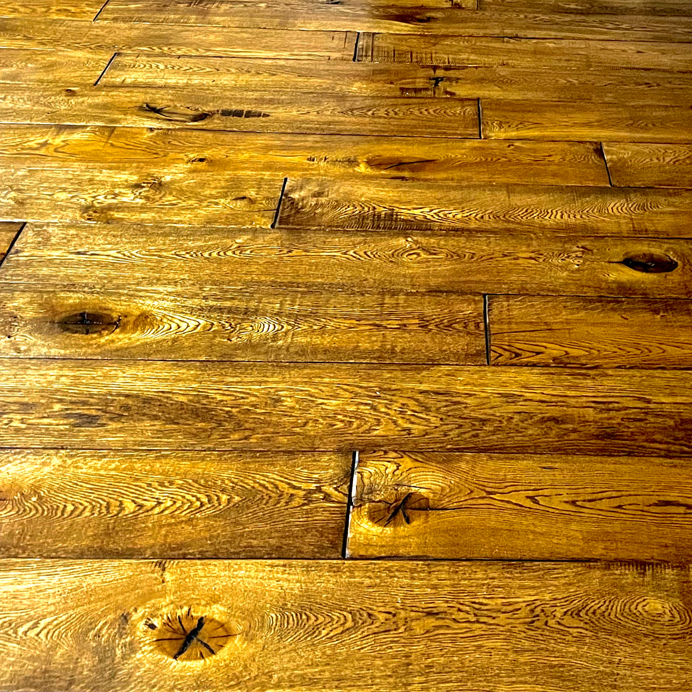 Golden hardwood floor planks with natural grain patterns and knots