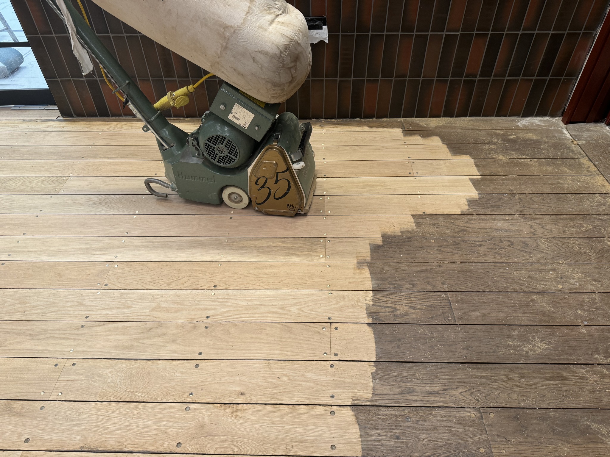 Floor sanding machine on wooden deck showing before and after