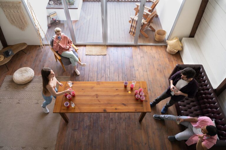 Overhead view of friends playing beer pong in modern living room