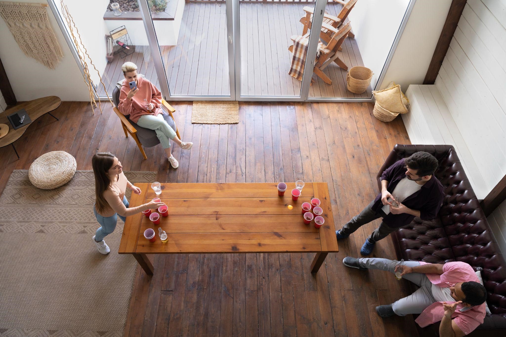 Overhead view of friends playing beer pong in modern living room