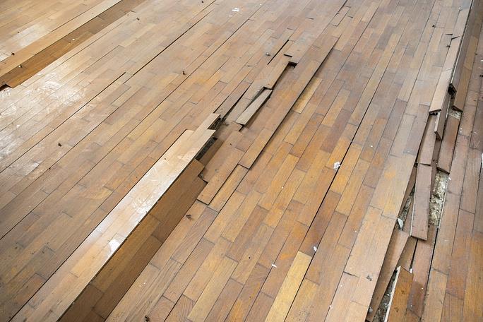 Damaged wooden floor with lifted and warped planks
