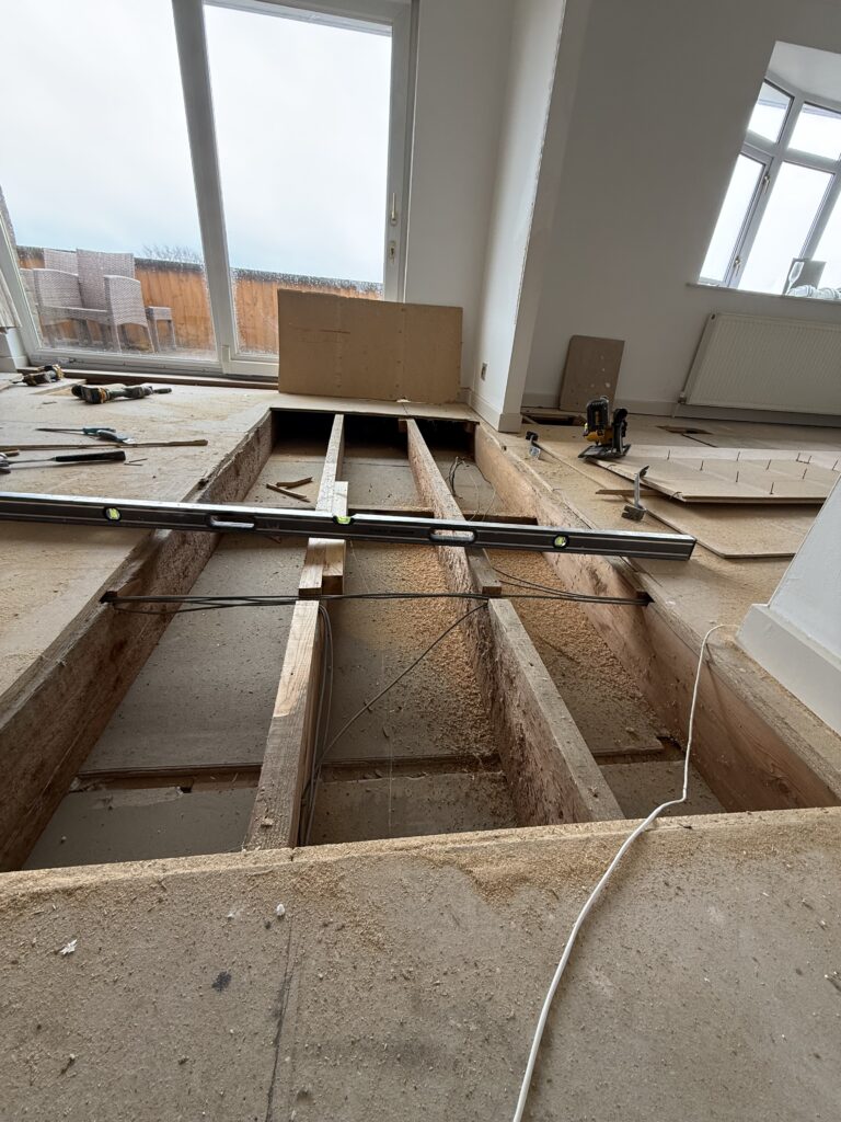 Construction site interior with exposed floor joists and supports