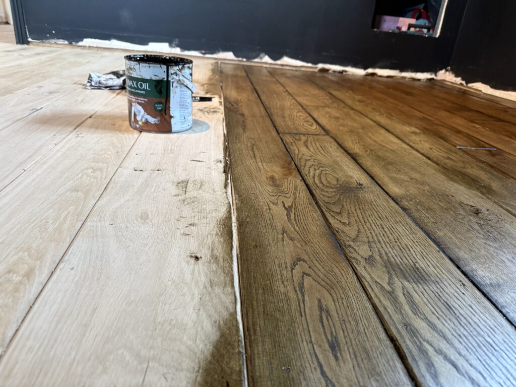 Wood floor installation with wax oil tin and dark wall