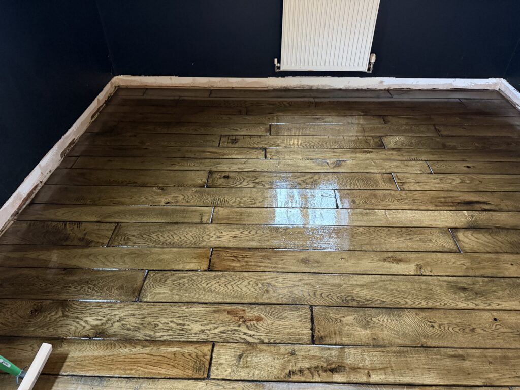 Wooden plank flooring with white wall radiator and dark walls