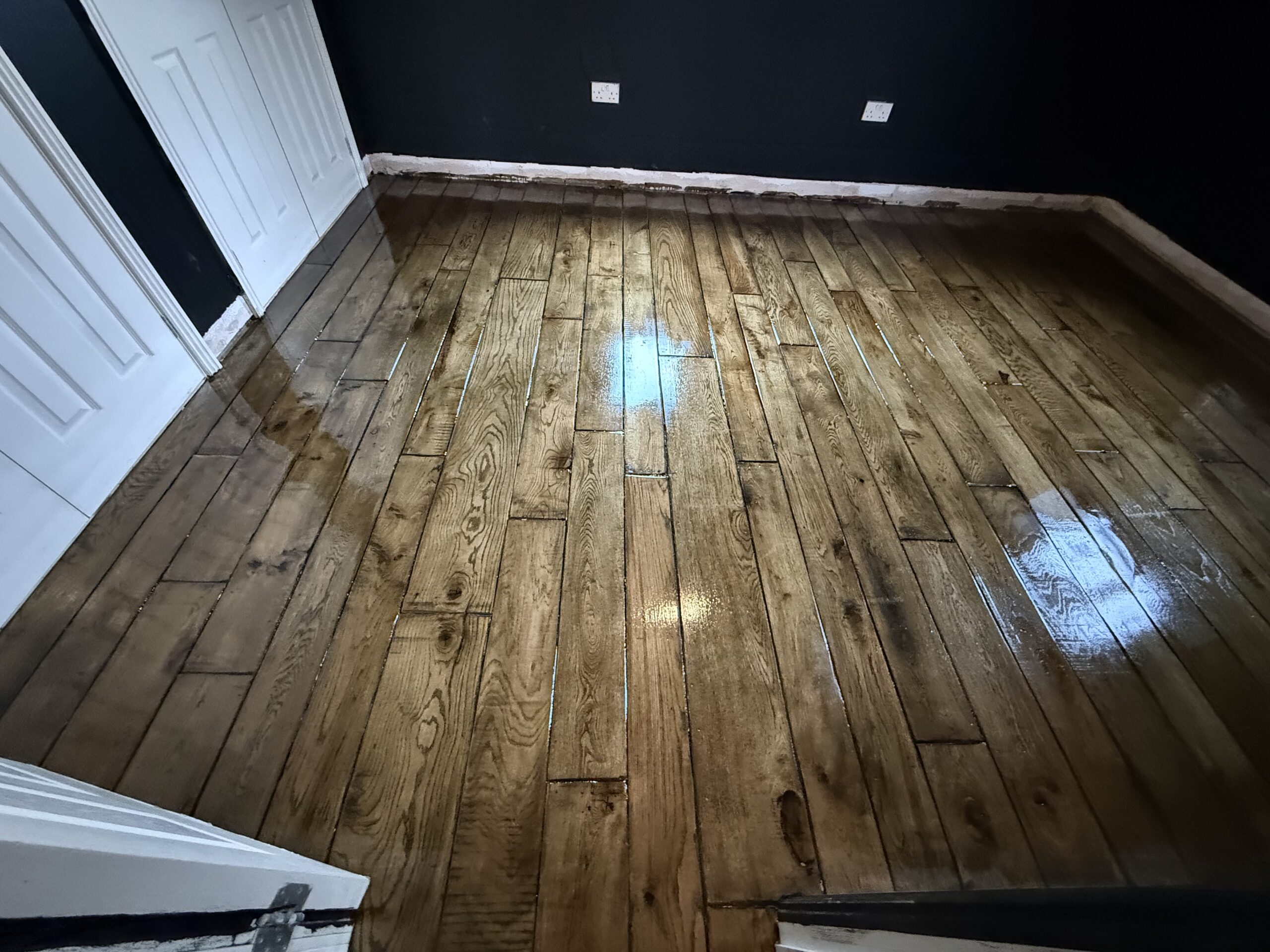 Wooden floor with dark walls and white door frame
