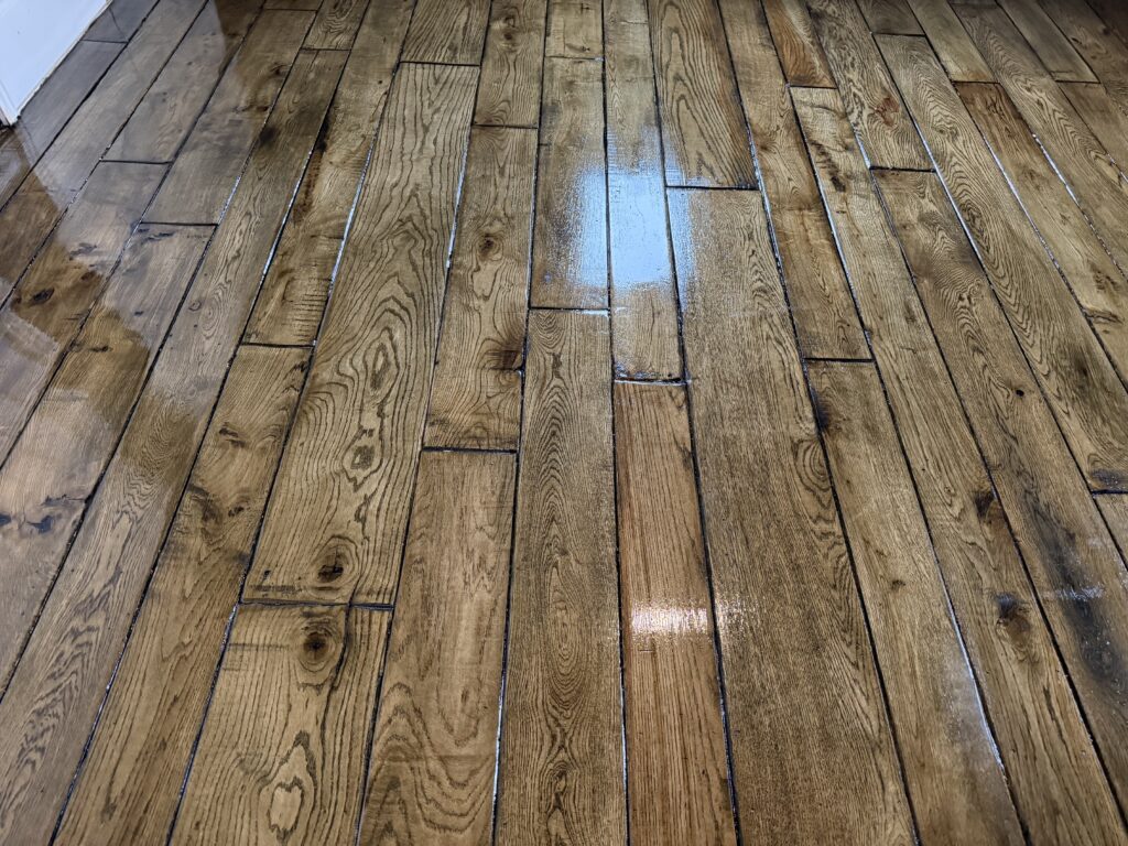 Wooden hardwood flooring with staggered plank pattern and light reflection