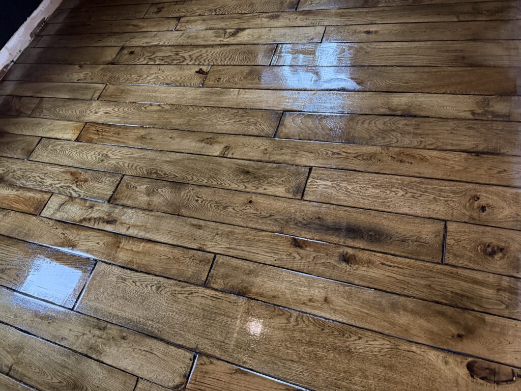 Hardwood floor with light blue paint patches during refinishing