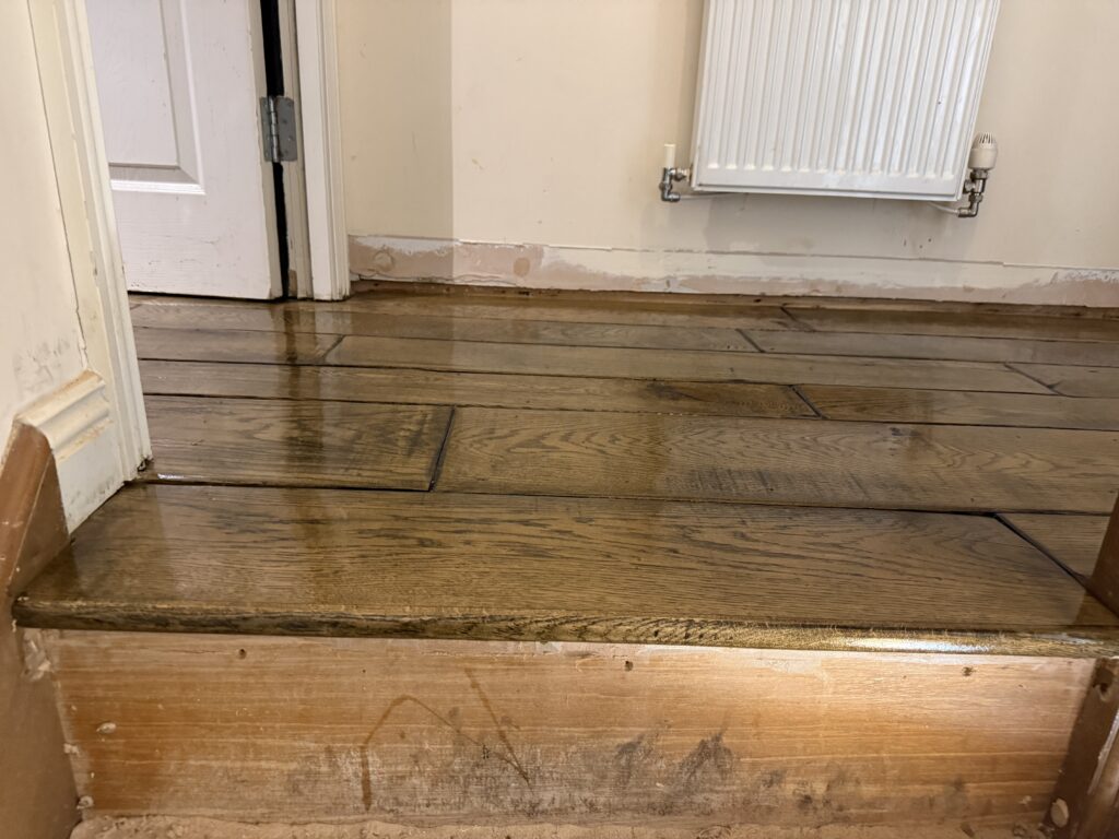Wet wooden floor in empty room during renovation