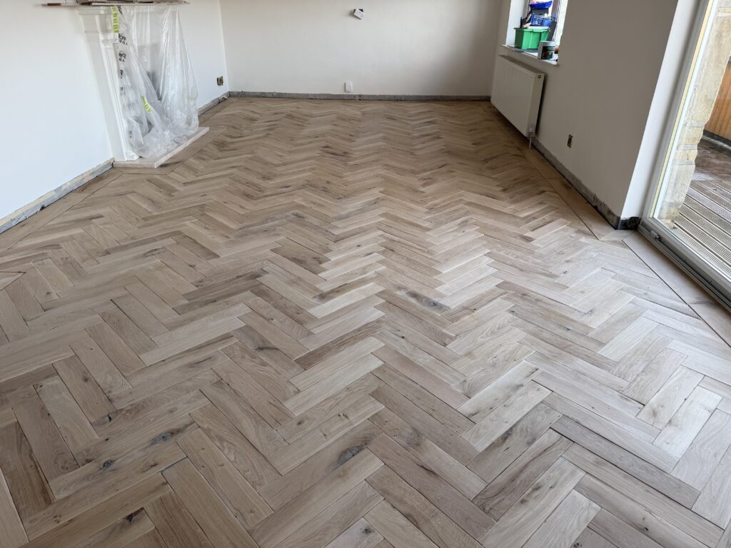 Empty room with herringbone wood flooring installation