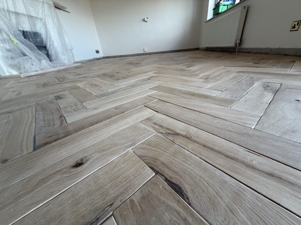 Herringbone wooden flooring installation in progress indoors