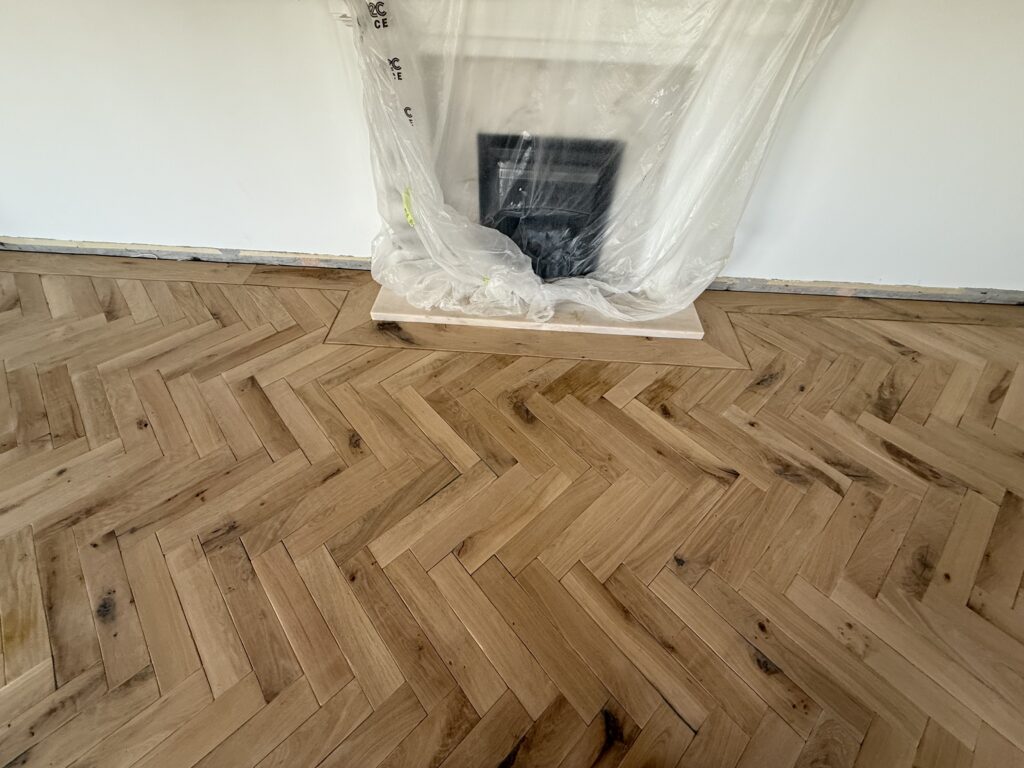 Herringbone wooden flooring with protective plastic sheeting covering
