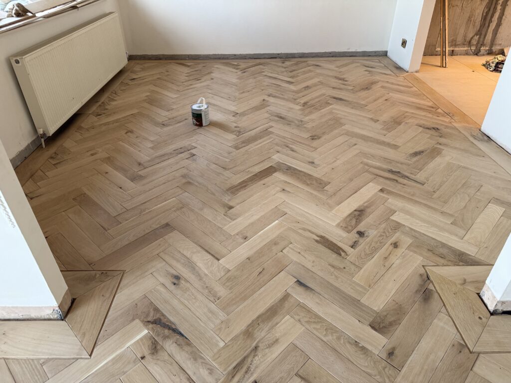 Herringbone wooden flooring in empty room during installation