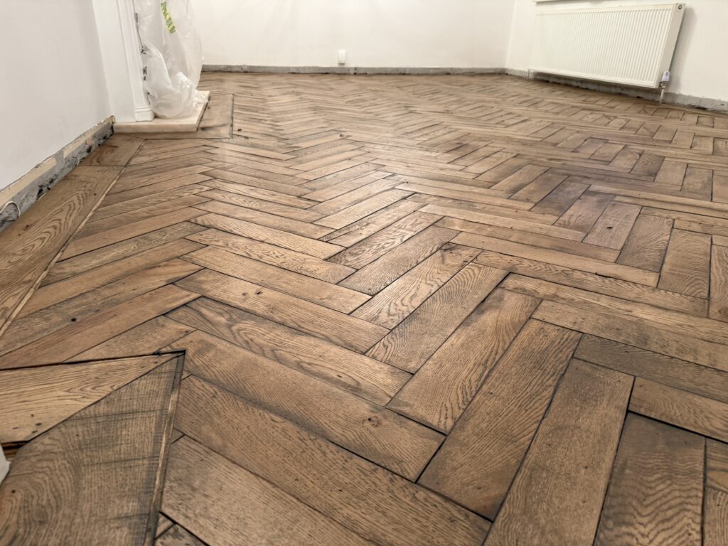 Herringbone wooden parquet flooring in unfurnished room