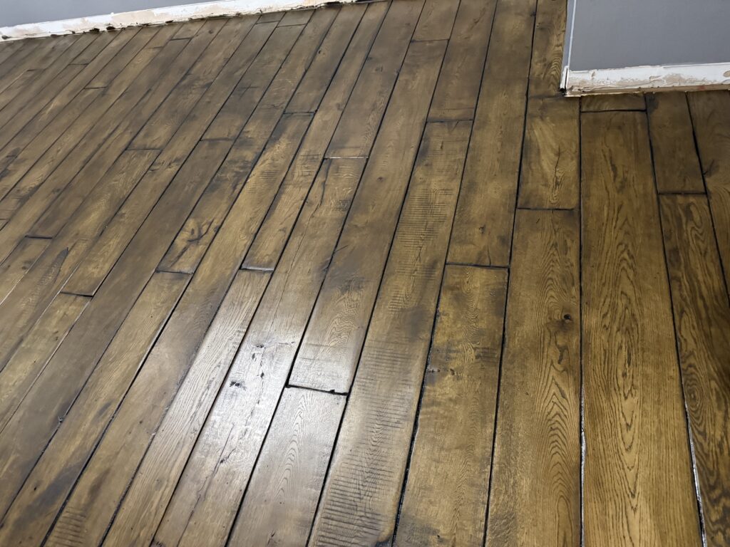 Wooden laminate flooring in herringbone pattern with white trim