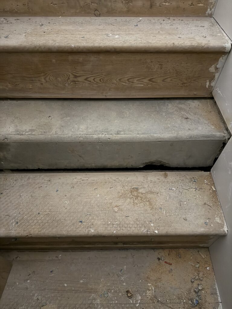Concrete staircase with wooden nosing and debris