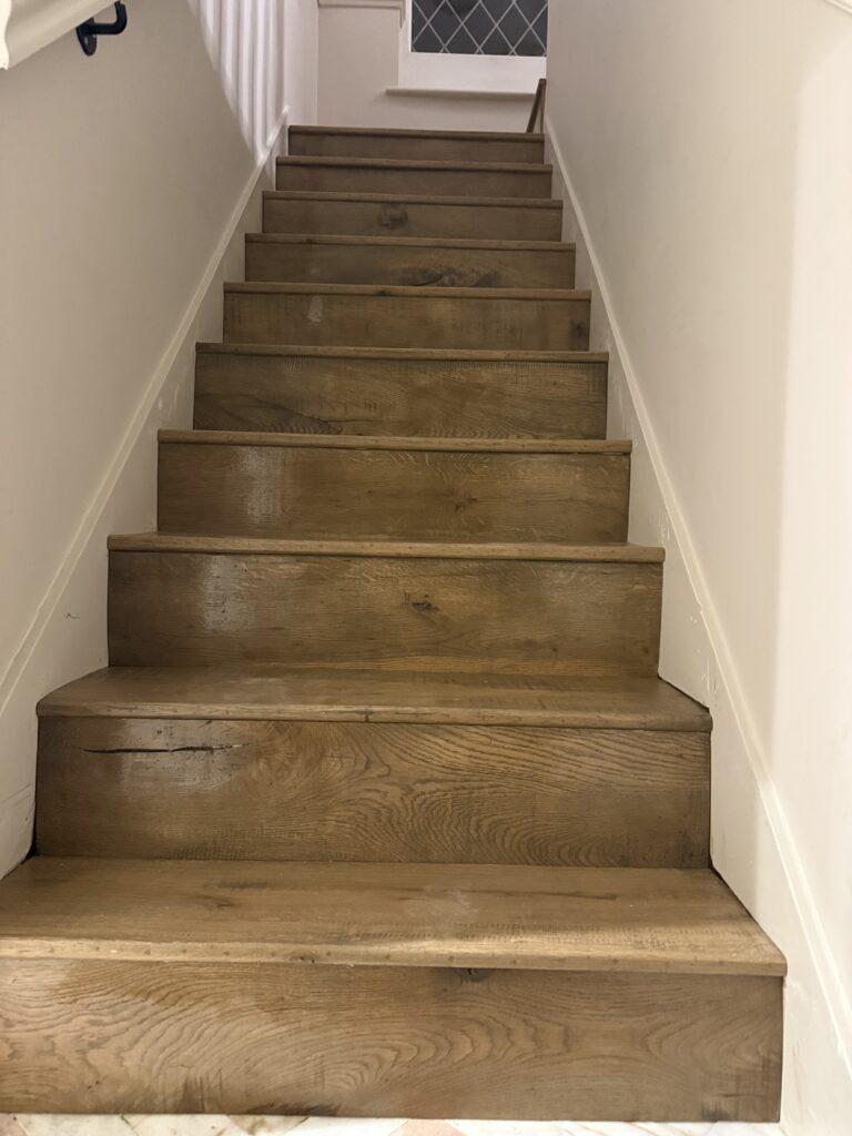Wooden staircase with white walls and handrail
